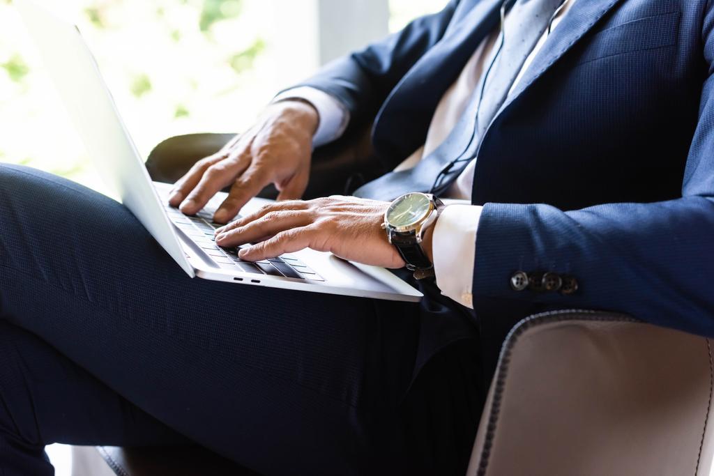 vista ritagliata di uomo d'affari in giacca e cravatta utilizzando il computer portatile in hotel
  - Foto, immagini