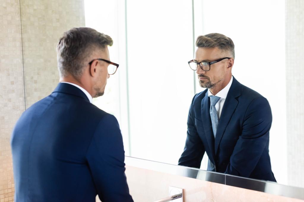 bell'uomo d'affari in abbigliamento formale e occhiali guardando lo specchio
  - Foto, immagini