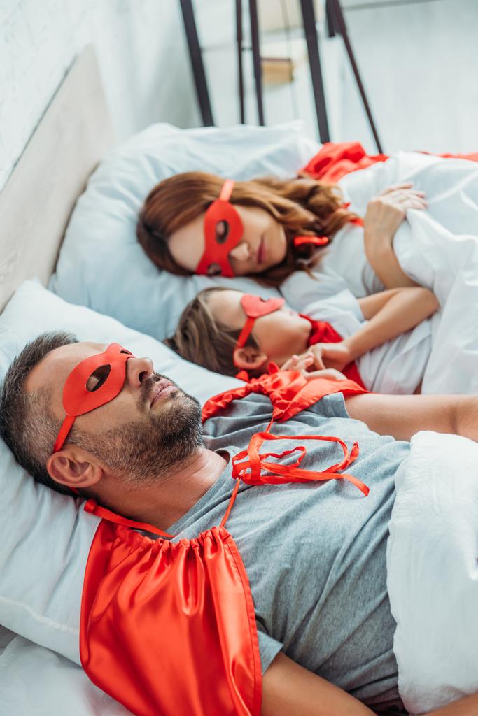 Selektiver Fokus von Mama, Papa und Sohn, die in Superhelden-Kostümen im Bett schlafen - Foto, Bild