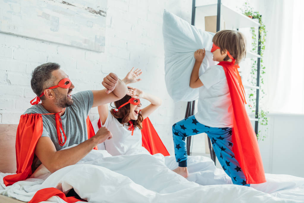 parents gais en costumes de super-héros se battant avec son fils tenant oreiller
 - Photo, image