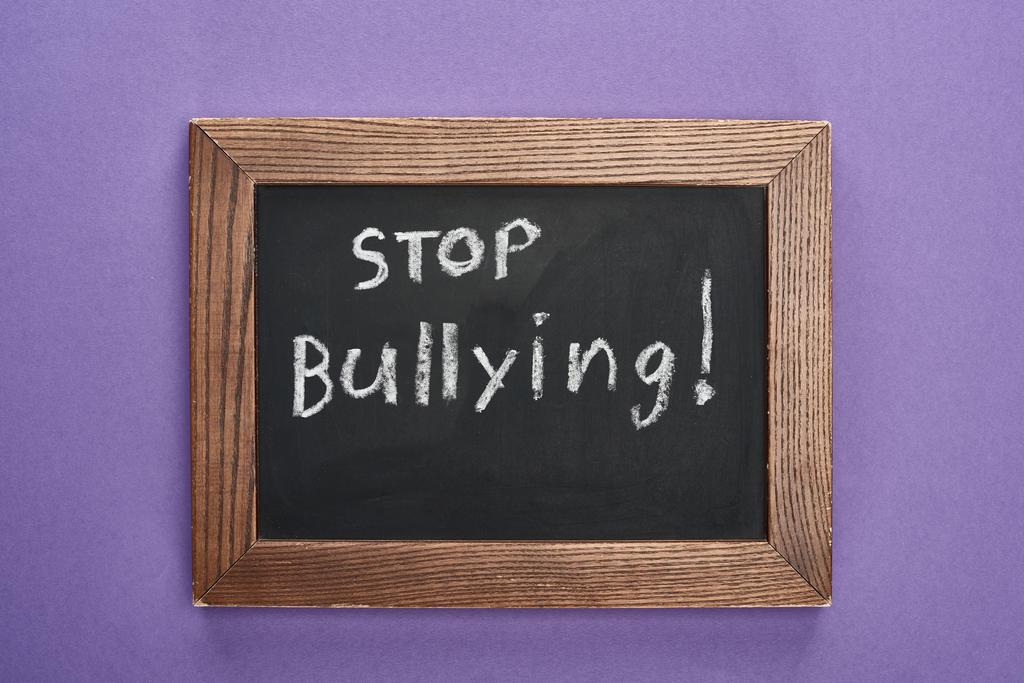 vista superior de quadro-negro em moldura de madeira com stop bullying lettering no fundo roxo
 - Foto, Imagem