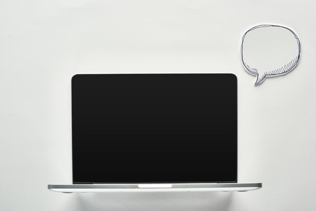 portátil con pantalla en blanco sobre fondo blanco cerca de la burbuja del habla vacía, concepto de cyberbullying
 - Foto, Imagen
