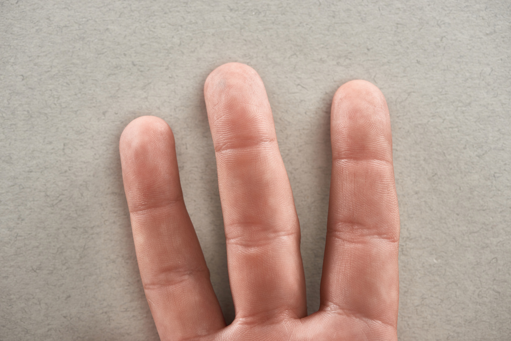 μερική θέα του ανθρώπου που δείχνει τρία δάχτυλα σε γκρίζο φόντο - Φωτογραφία, εικόνα