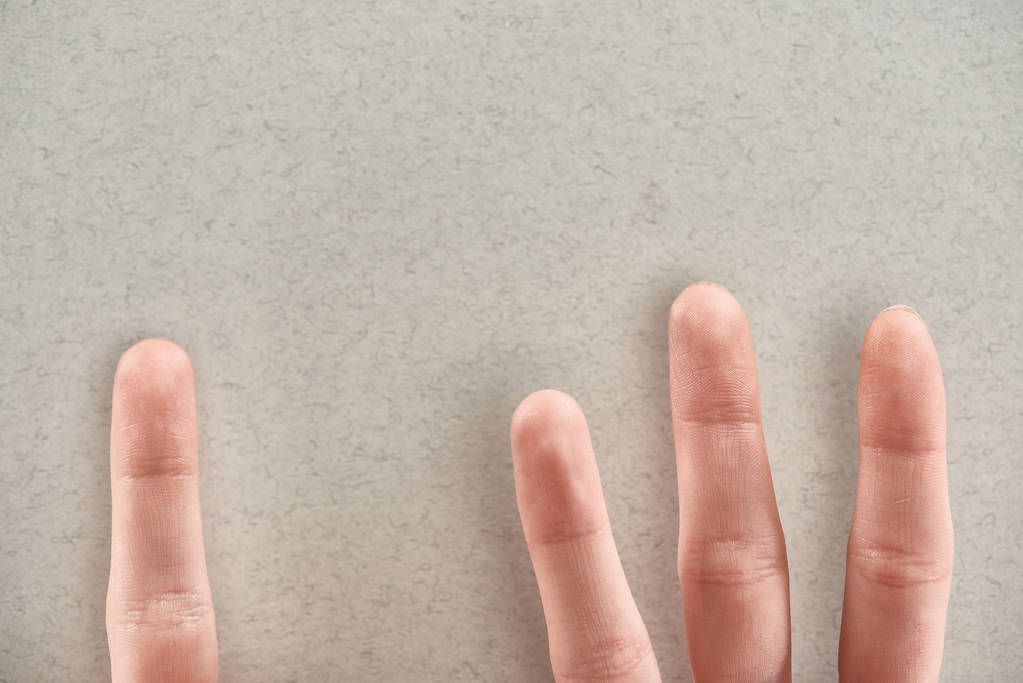 vista recortada del hombre mostrando los dedos que simbolizan a los abusadores y la víctima sobre un fondo gris
 - Foto, imagen