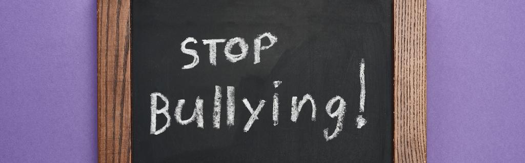 panoramic shot of chalkboard in wooden frame with stop bullying lettering on purple background - Photo, Image