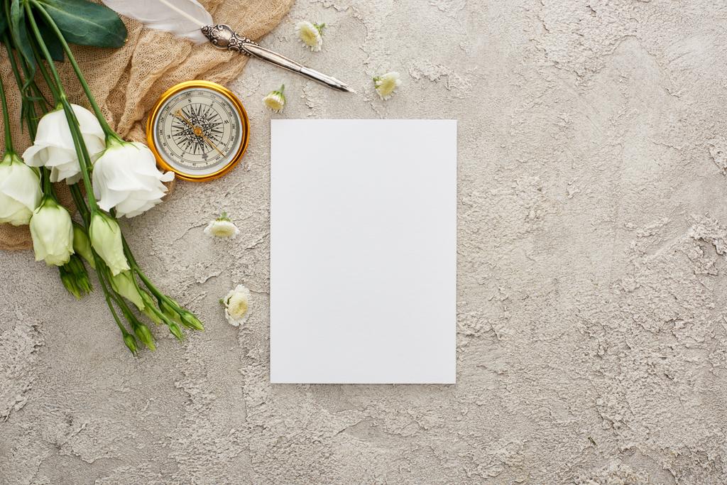 boş kart, altın pusula ve gri dokulu yüzeyüzerinde beyaz eustoma çiçekler yakın bej çuval bezi üzerinde quill kalem üst görünümü - Fotoğraf, Görsel