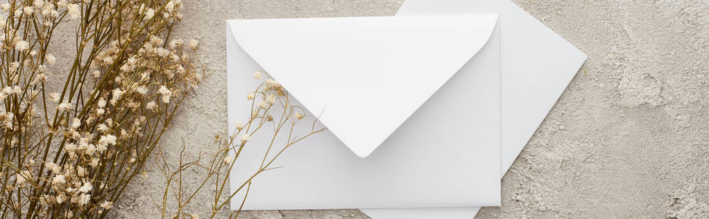 tiro panorâmico de envelope branco perto de flores na superfície texturizada
 - Foto, Imagem