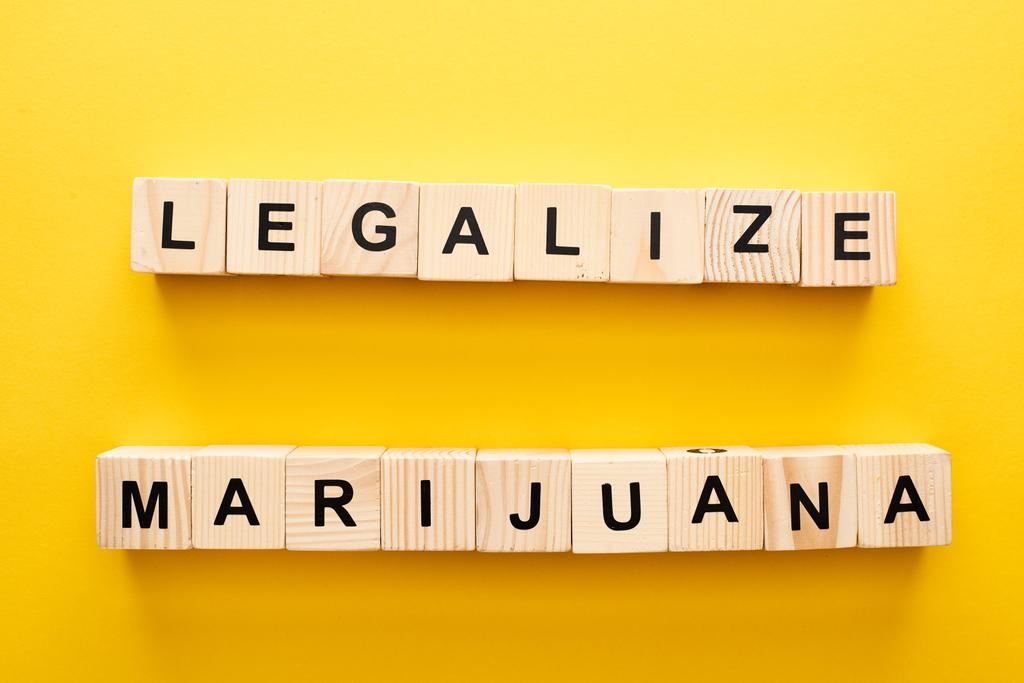 Κορυφαία όψη των ξύλινων μπλοκ με νομιμοποιήσει γράμματα μαριχουάνας σε κίτρινο φόντο - Φωτογραφία, εικόνα