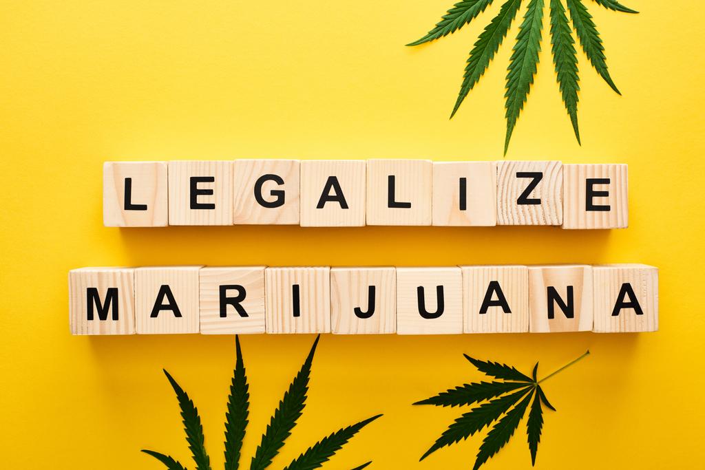 Widok z góry konopi liści i drewnianych bloków z legalizacji marihuany napis na żółtym tle - Zdjęcie, obraz