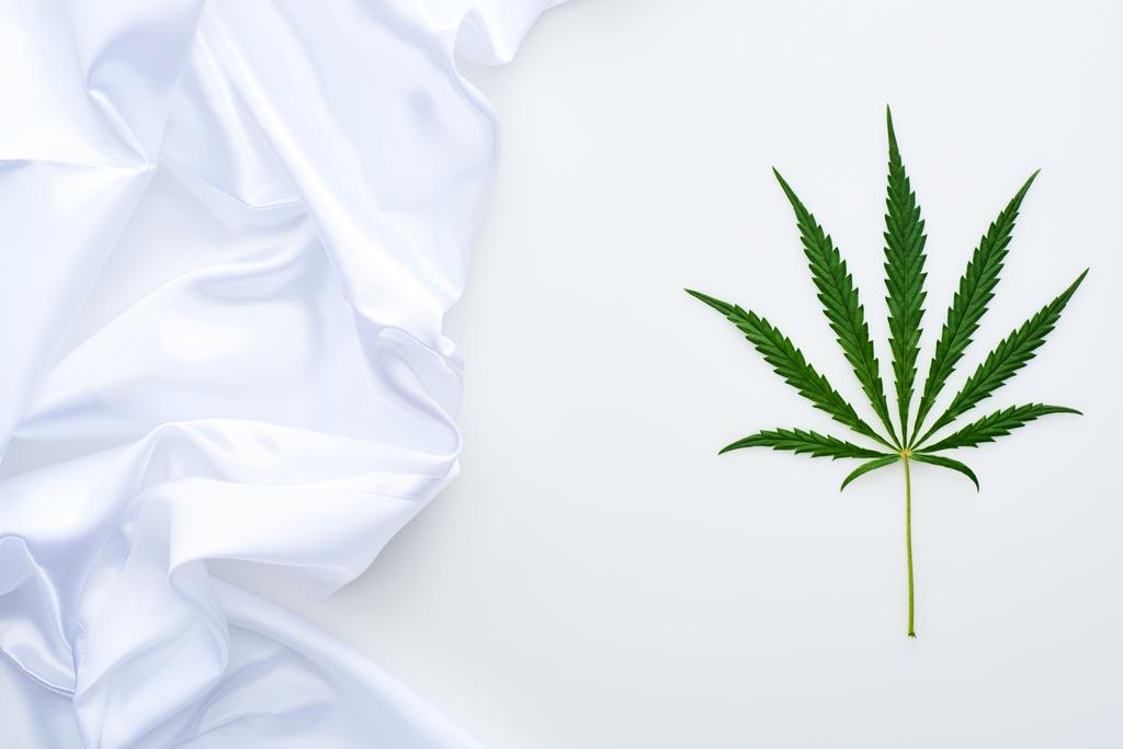 top view of green cannabis leaf near white flag on white background - Photo, Image
