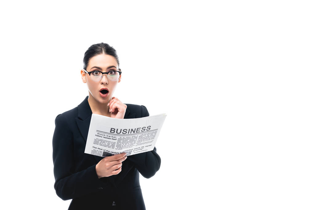 shocked businesswoman looking at camera while holding business newspaper isolated on white - Photo, Image