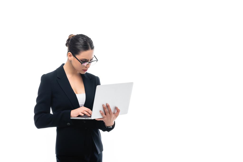 συγκεντρωμένη επιχειρηματίας σε γυαλιά που χρησιμοποιούν laptop απομονώνονται σε λευκό - Φωτογραφία, εικόνα