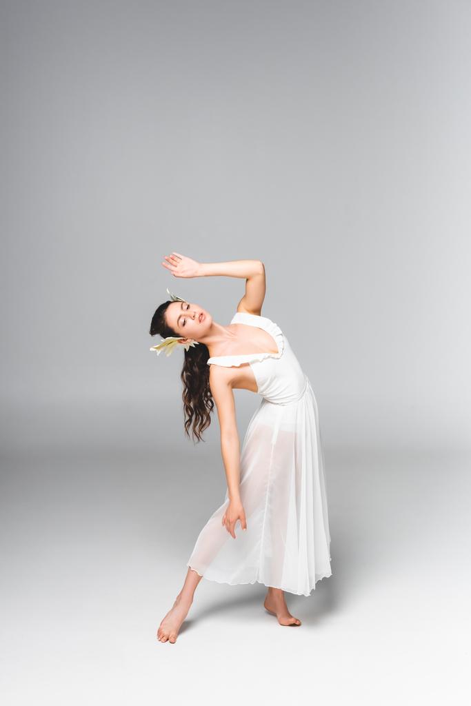 витончена, приваблива балерина в білій сукні танцює на сірому фоні
 - Фото, зображення