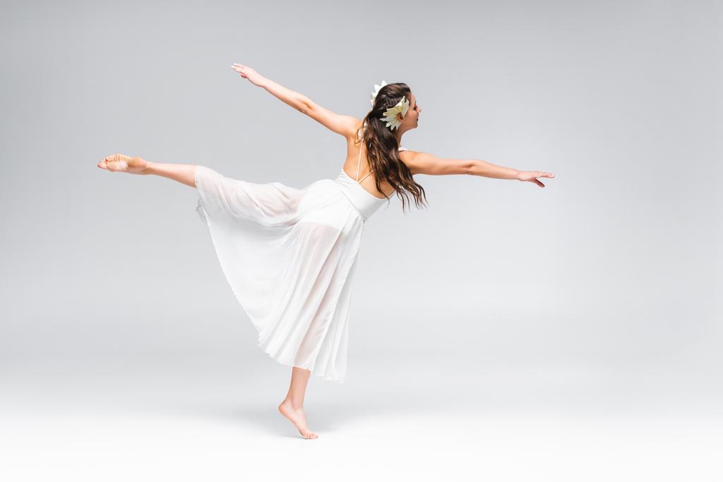 beautiful, elegant ballerina in white dress dancing on grey background - Photo, Image
