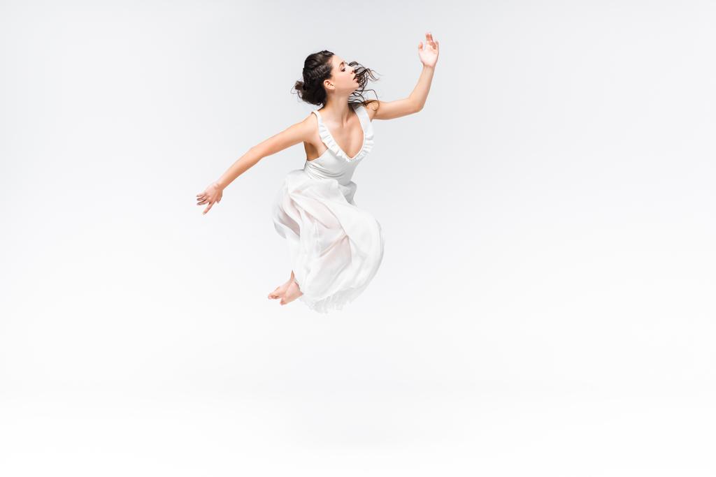 όμορφη, χαριτωμένη μπαλαρίνα άλμα στο χορό σε γκρίζο φόντο - Φωτογραφία, εικόνα