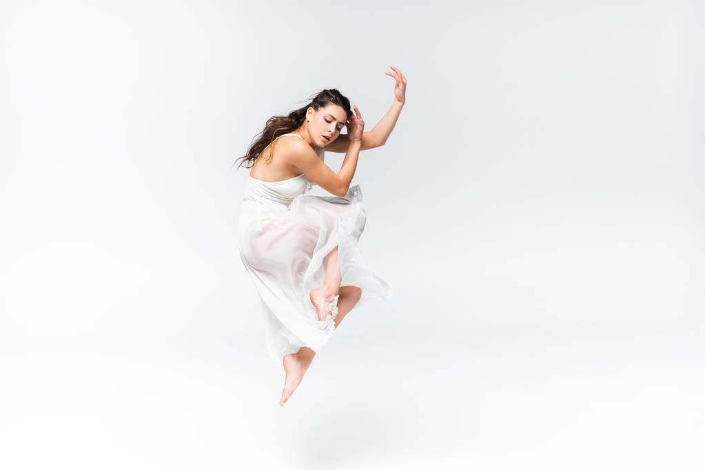 graceful, elegant ballerina in white dress dancing on grey background - Photo, Image