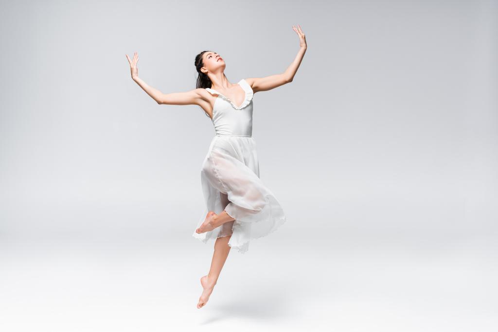 joven bailarina elegante en vestido blanco bailando sobre fondo gris
 - Foto, imagen