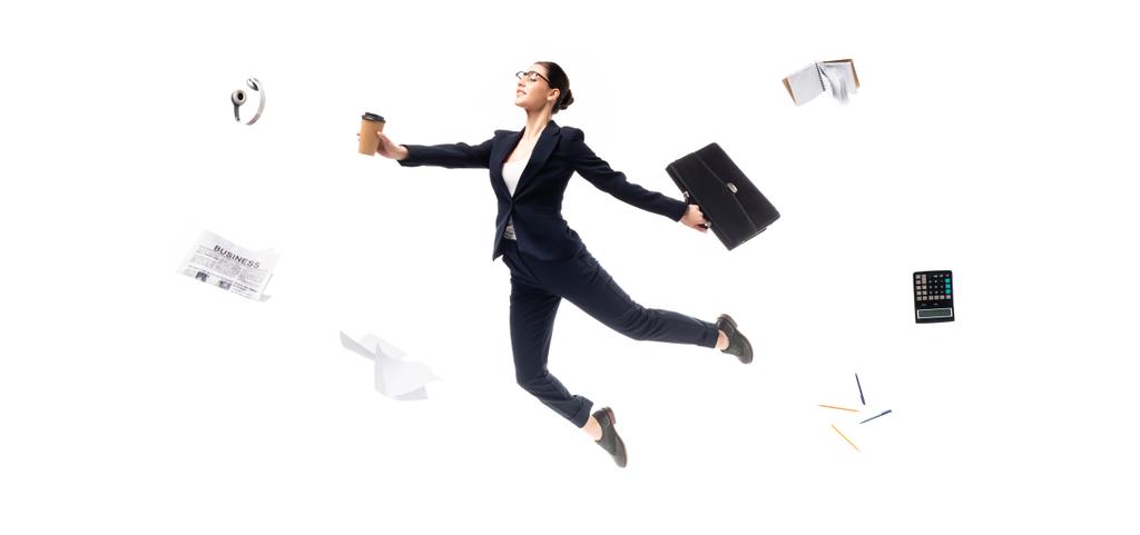 панорамный снимок предпринимательницы, держащей кофе, чтобы пойти и портфель во время левитации окруженные наушники, газеты, калькулятор и канцелярские принадлежности изолированы на белом
 - Фото, изображение