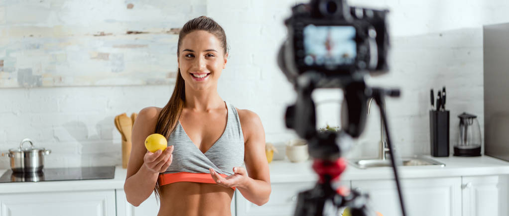 panoramic shot of happy girl holding lemon and looking at digital camera  - Photo, Image
