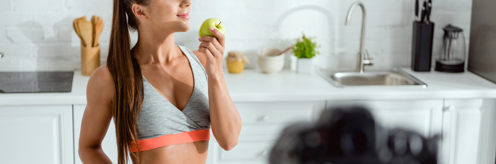 tiro panorâmico de mulher feliz cheirando maçã saborosa
  - Foto, Imagem