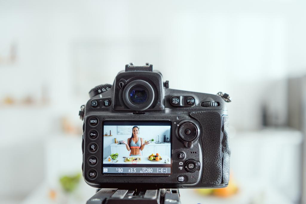 mise au point sélective de l'appareil photo numérique avec fille heureuse gestuelle près des fruits à l'écran
  - Photo, image