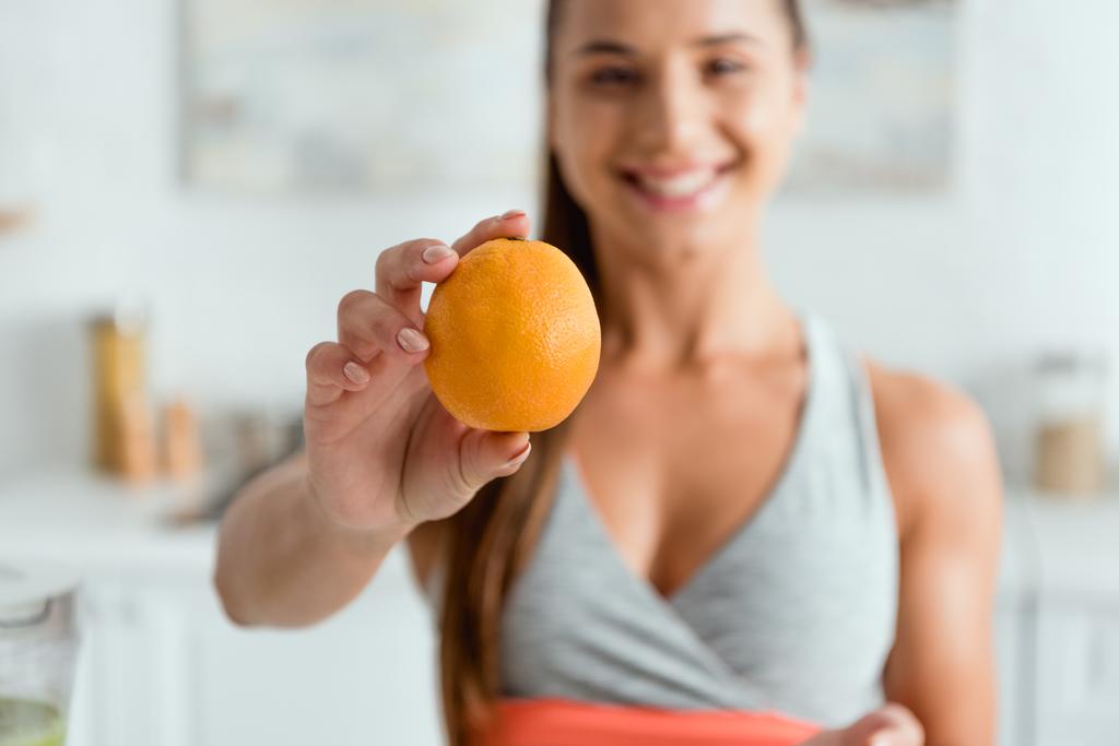 foco seletivo da jovem mulher feliz segurando laranja saborosa
  - Foto, Imagem