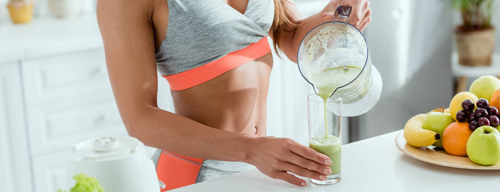 panoramic shot of girl holding glass while pouring smoothie from blender  - Photo, Image