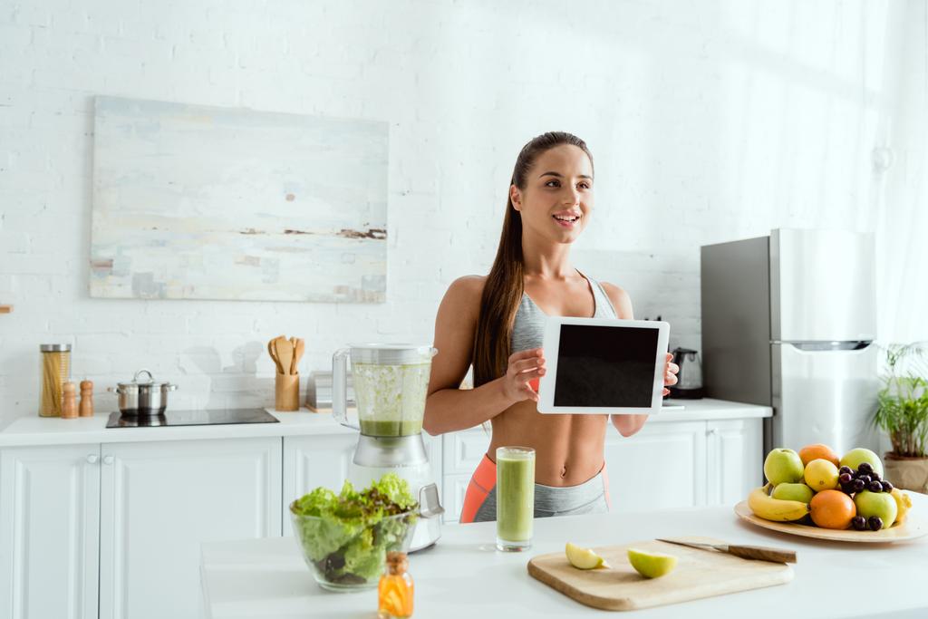 onnellinen nainen tilalla digitaalinen tabletti tyhjä näyttö keittiössä
  - Valokuva, kuva