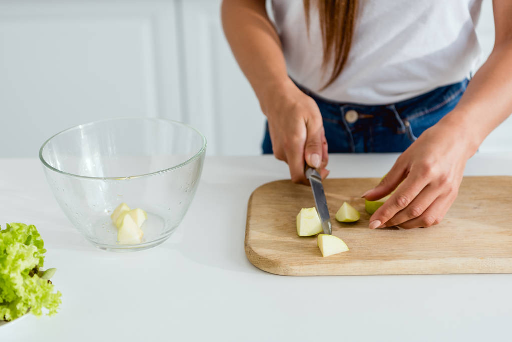 bijgesneden beeld van jonge vrouw snijden groene appel op hakken Board  - Foto, afbeelding