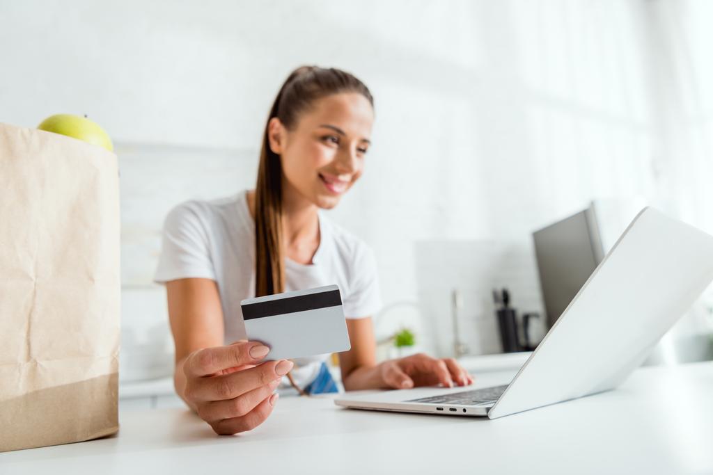 foyer sélectif de fille heureuse tenant la carte de crédit et en utilisant un ordinateur portable
  - Photo, image