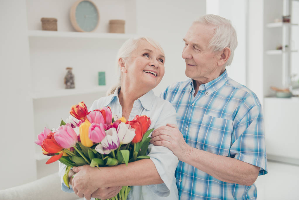 Portréja ő ő ő két szép vonzó szép vidám vidám pályázati emberek nagymama kezében a kezében nagy friss természetes tulipán Gratula Üdvözlet tavasszal világos fehér belső nappali ház - Fotó, kép