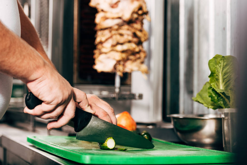 обрізаний вид кухаря, що ріже огірки на дошці
 - Фото, зображення