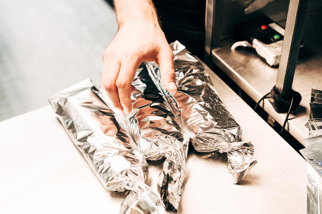 cropped view of man and doner kebabs in aluminium foil - Photo, Image