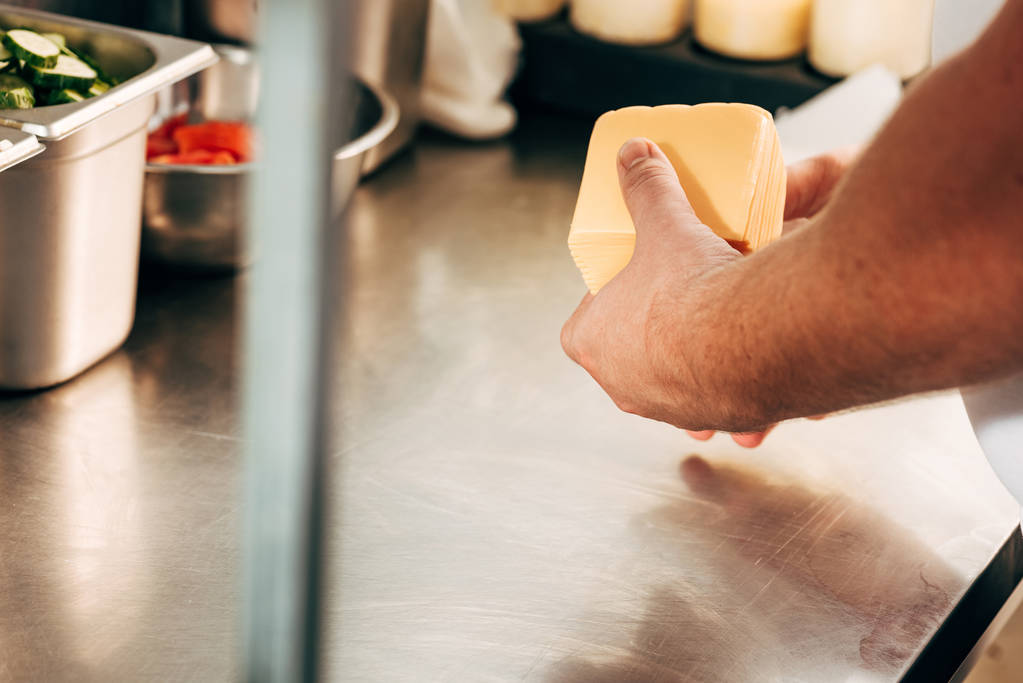 vista cortada do cozinheiro segurando queijo no local de trabalho
 - Foto, Imagem
