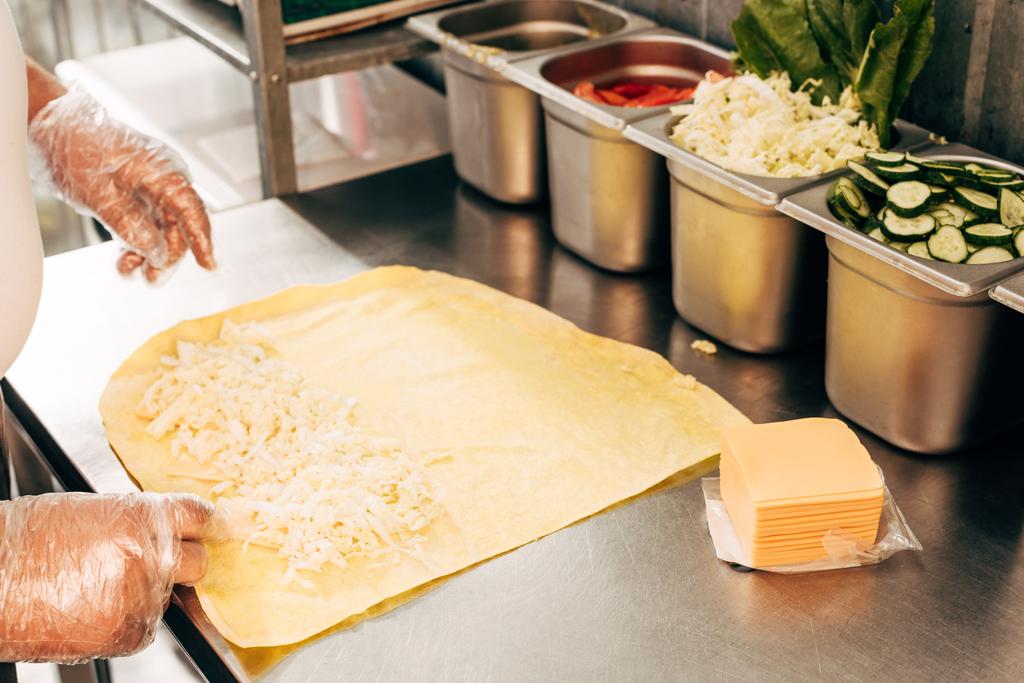 Ausgeschnittener Blick auf Koch in Handschuhen, der Dönerspieße zubereitet - Foto, Bild