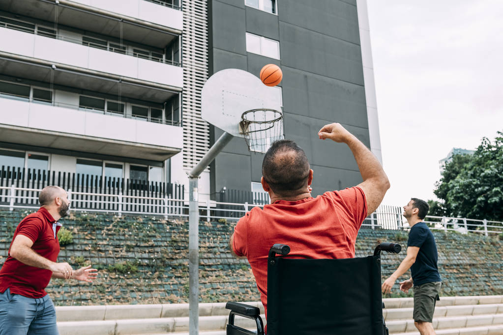 hombre discapacitado lanzando a la cesta con dos amigos
 - Foto, Imagen