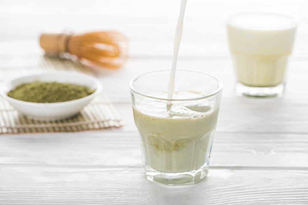 Πράσινο τσάι Matcha με γάλα στον άσπρο πίνακα  - Φωτογραφία, εικόνα