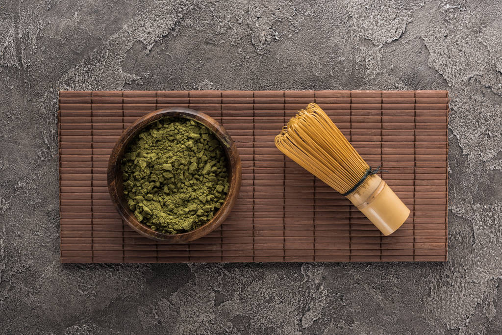vista superior del polvo de té matcha con batidor en estera de bambú en mesa de piedra oscura
 - Foto, imagen
