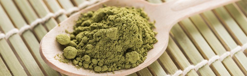 Nahaufnahme eines Holzlöffels mit Puder aus grünem Matcha-Tee auf Bambusmatte - Foto, Bild