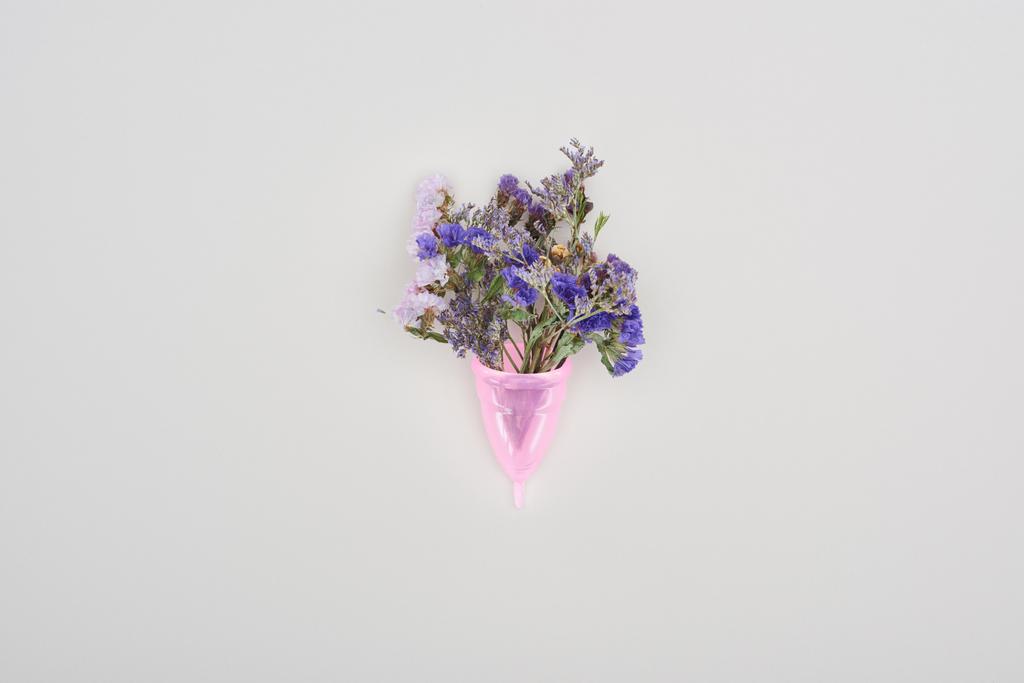 top view of pink plastic menstrual cup with wildflowers isolated on grey - Photo, Image