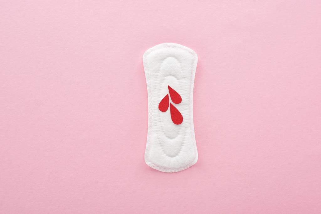 top view of white sanitary napkin with blood drops on pink background - Photo, Image