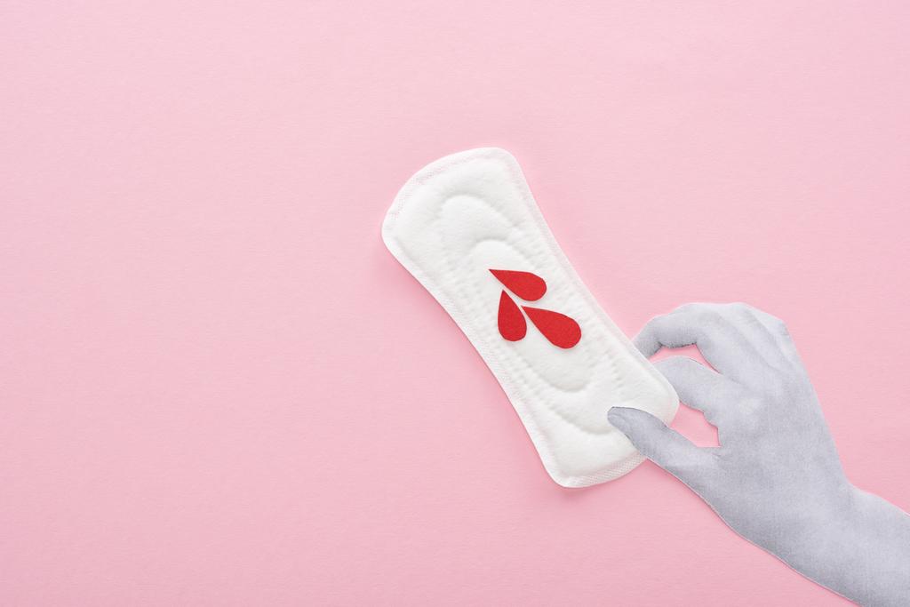 vista recortada de la mano sosteniendo la servilleta sanitaria blanca con gotas de sangre sobre fondo rosa
 - Foto, imagen