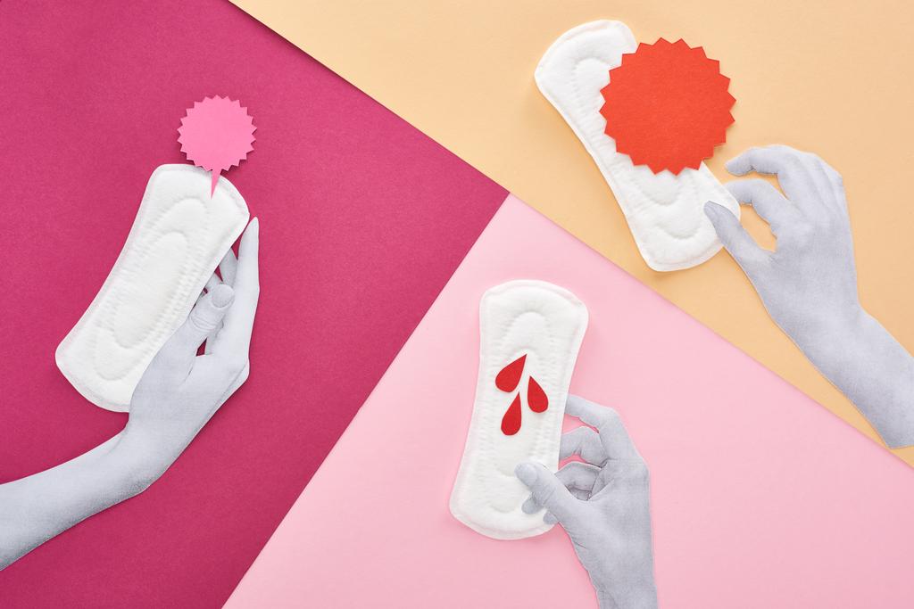 vista superior de las manos cortadas de papel con toallas sanitarias blancas cerca de tarjetas vacías y gotas de sangre sobre fondo púrpura, rosa y beige
 - Foto, imagen