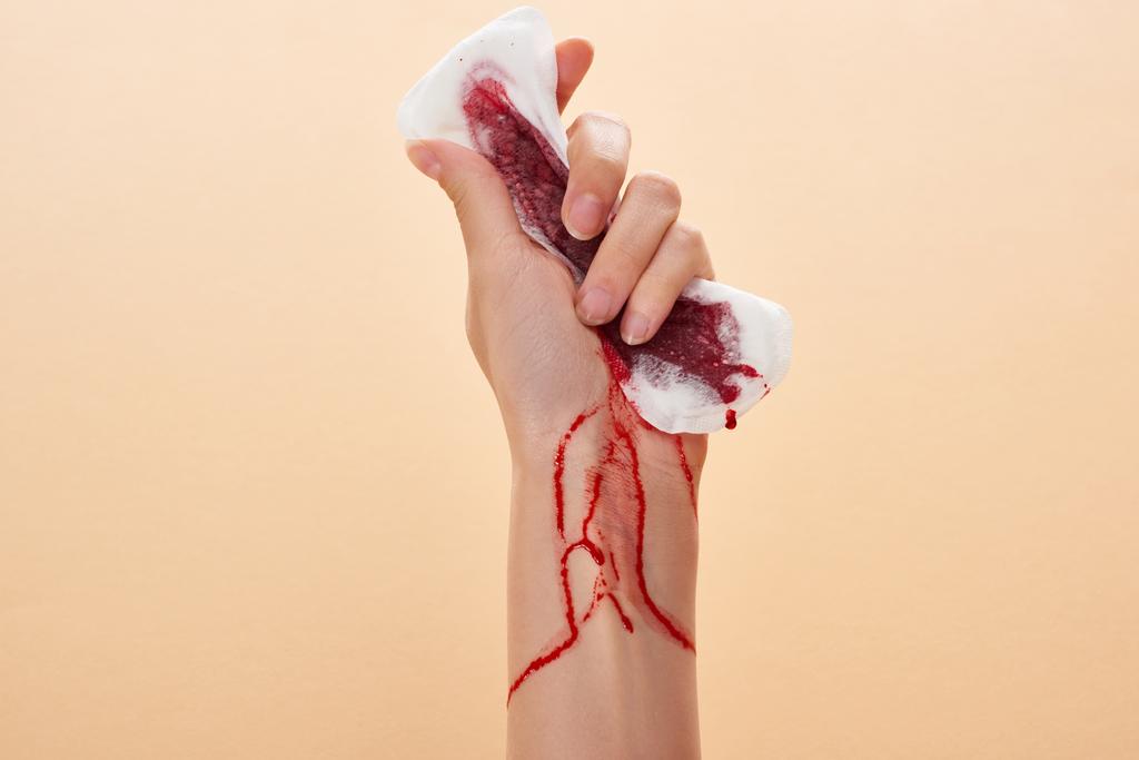 partial view of woman squeezing sanitary towel with blood isolated on beige - Photo, Image