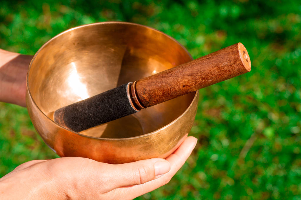Bronze singing bowl in female hands with a wooden stick to extra - Photo, Image