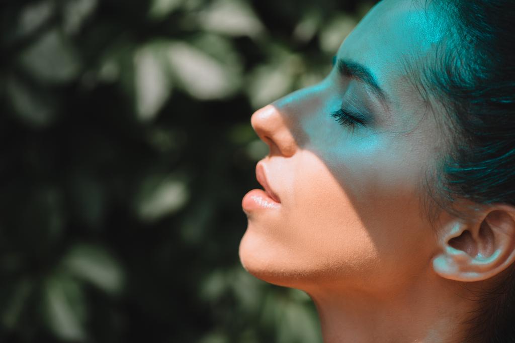 Zijaanzicht van blauwe bliksem op mooie vrouw met gesloten ogen  - Foto, afbeelding