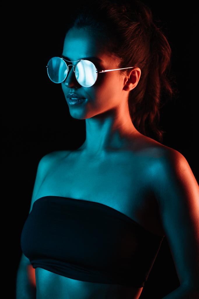 stylische junge Frau mit Sonnenbrille isoliert auf schwarz  - Foto, Bild