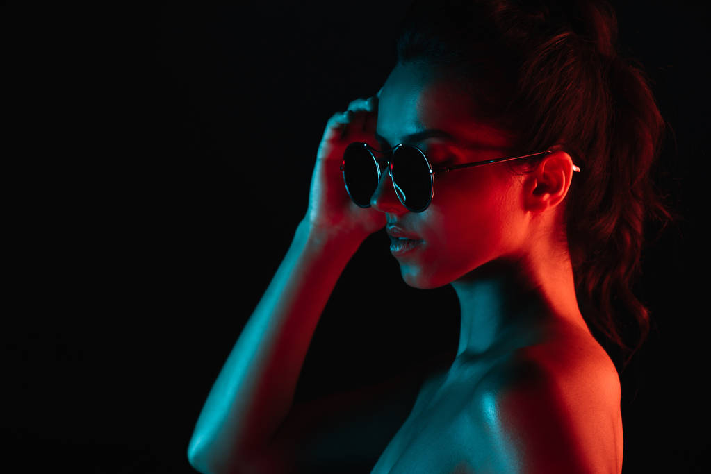 приваблива молода жінка в сонцезахисних окулярах ізольована на чорному
  - Фото, зображення