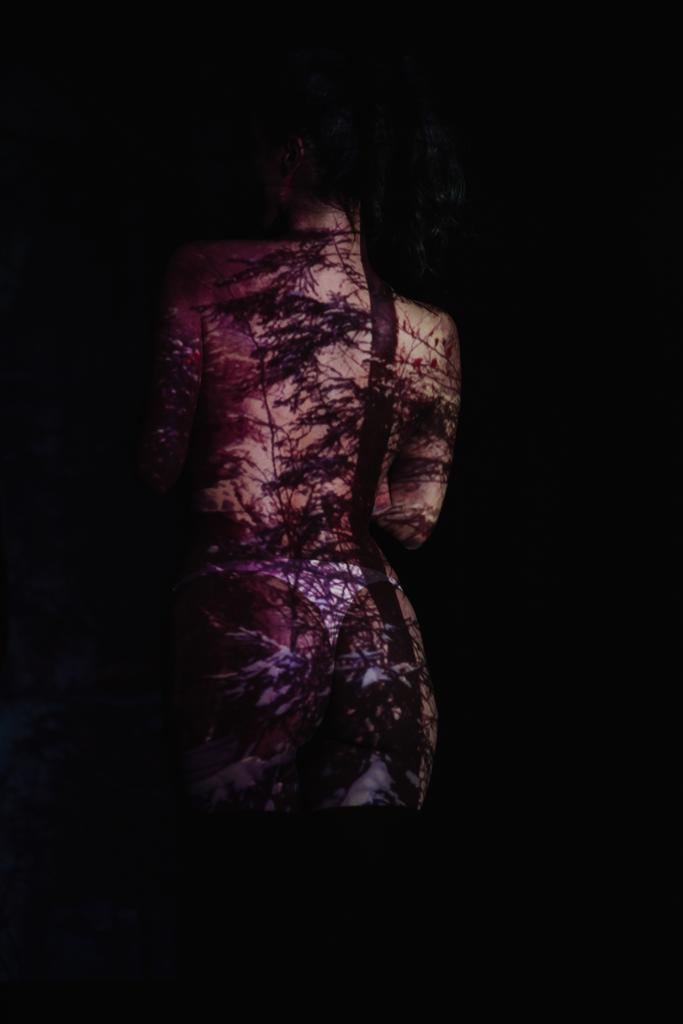 Achteraanzicht van Undressed meisje met schaduwen op lichaam op zwart  - Foto, afbeelding