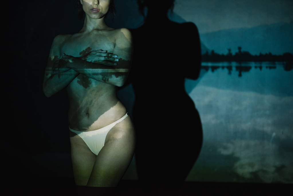 mujer joven desnuda de pie y cubriendo los pechos en negro
  - Foto, imagen